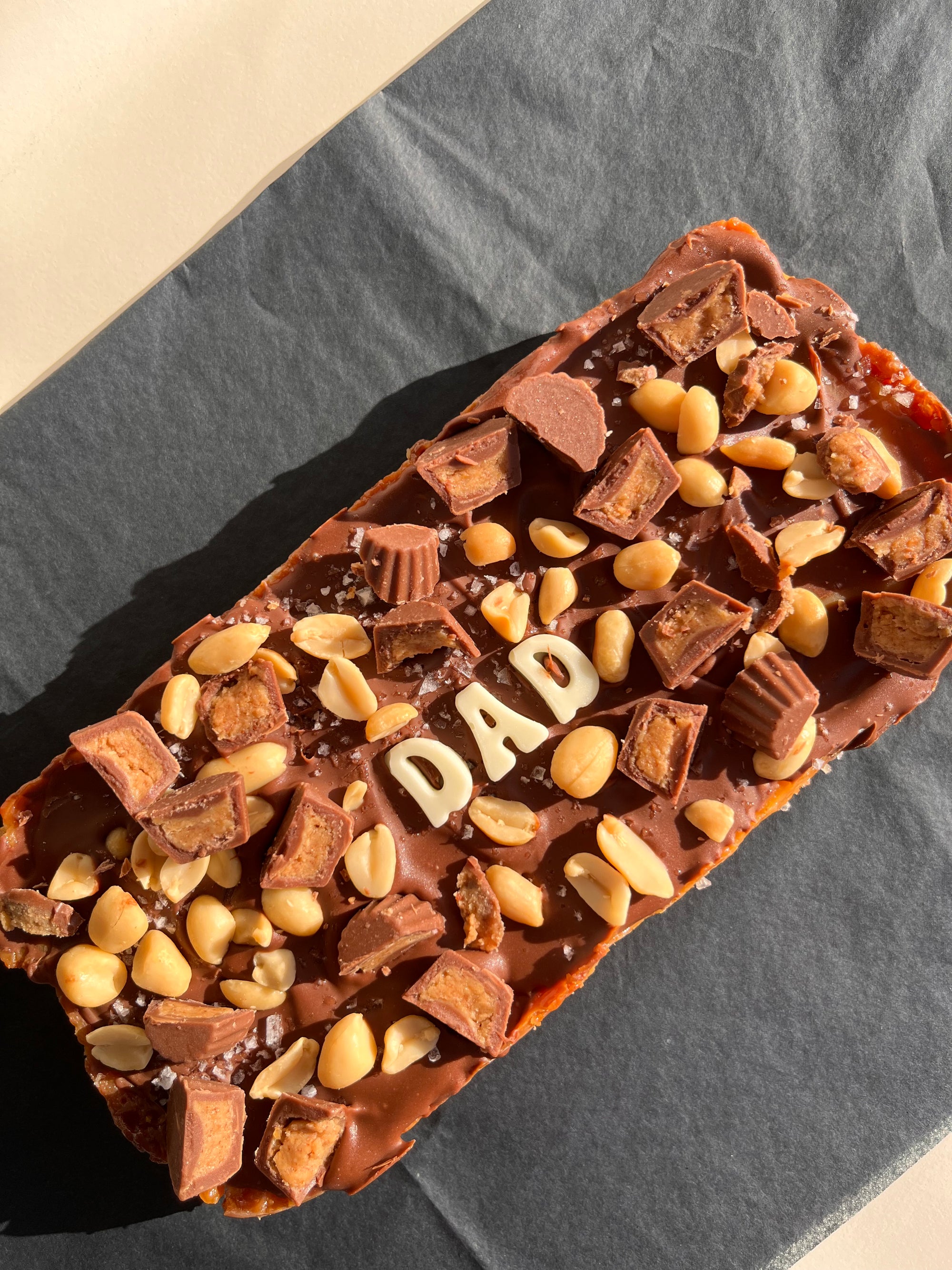 extra large reese&#39;s pieces caramel slice with &quot;dad&quot; written in white chocolate