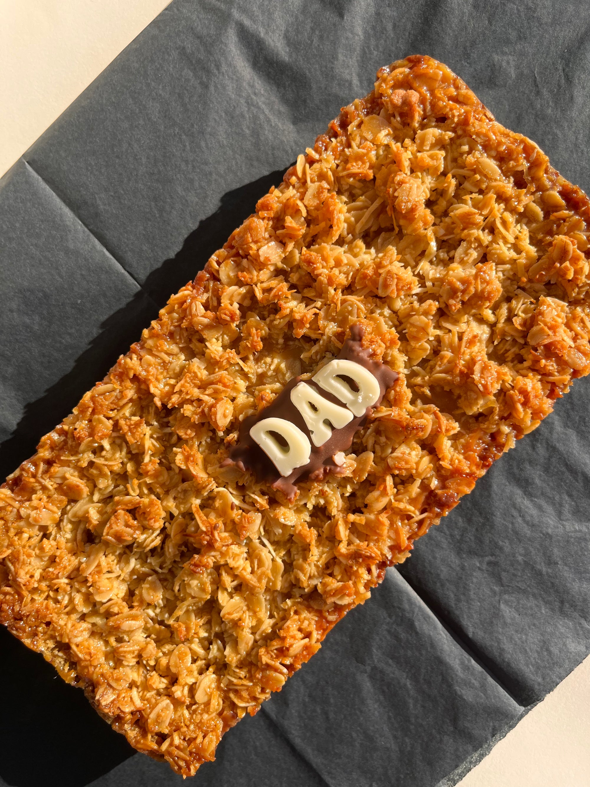 extra large golden oats caramel slice with &quot;dad&quot; written in white chocolate
